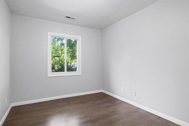 empty room with dark wood-type flooring and baseboards