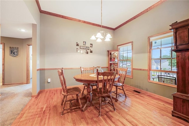 dining space featuring crown molding, light wood-style flooring, a chandelier, and baseboards