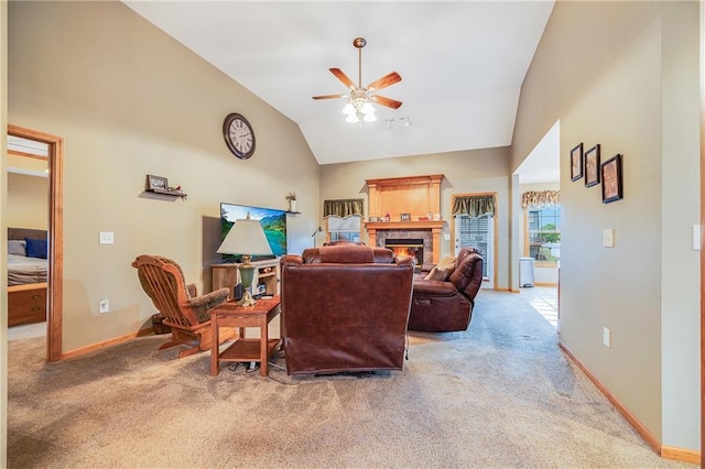 living room with vaulted ceiling, a ceiling fan, light colored carpet, a warm lit fireplace, and baseboards