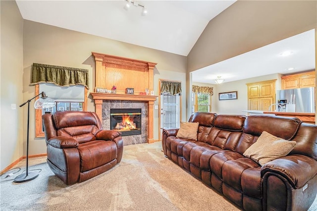 living area with light carpet, vaulted ceiling, a premium fireplace, and baseboards