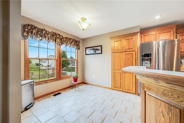 kitchen featuring stainless steel fridge with ice dispenser, baseboards, and light countertops