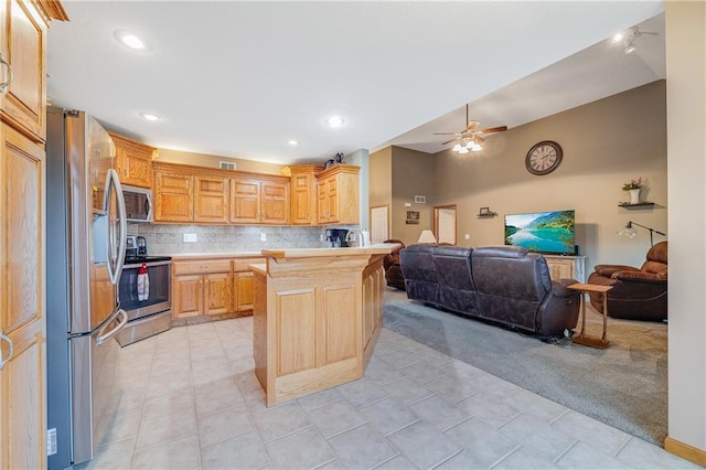 kitchen with appliances with stainless steel finishes, open floor plan, light countertops, a peninsula, and tasteful backsplash