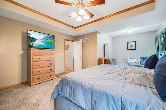 bedroom with light colored carpet, ornamental molding, baseboards, ceiling fan, and a tray ceiling