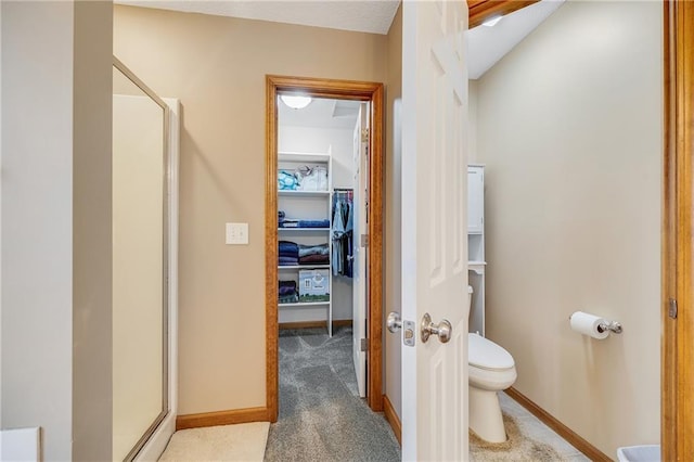 bathroom featuring a stall shower, toilet, and baseboards