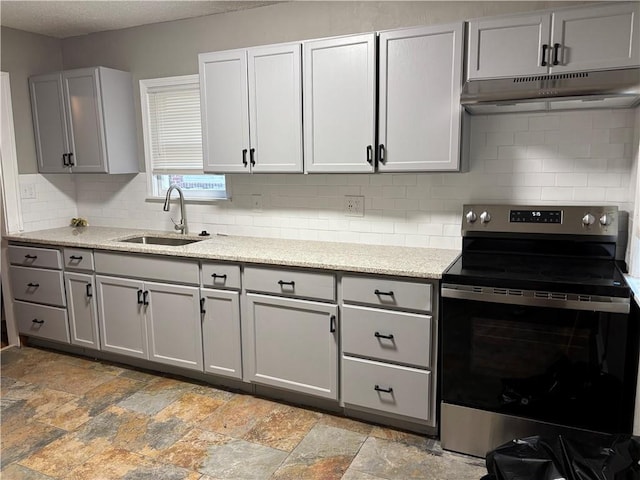 kitchen with stainless steel range with electric cooktop, under cabinet range hood, a sink, gray cabinetry, and a textured ceiling