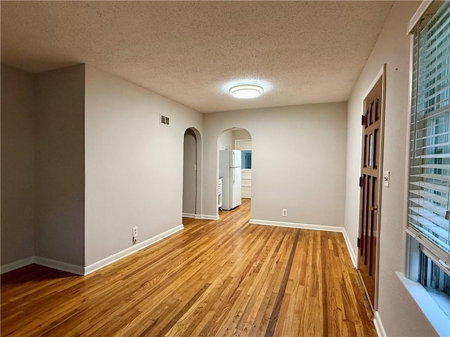 406 Bowen St, Linwood, KS 66052 - unfurnished room featuring wood finished floors, arched walkways, a textured ceiling, and baseboards