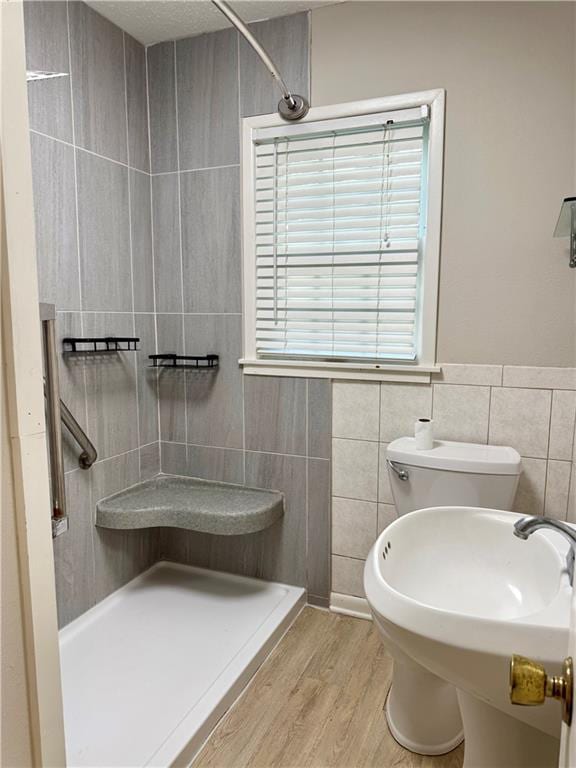 406 Bowen St, Linwood, KS 66052 - full bath with a tile shower, tile walls, wood finished floors, toilet, and plenty of natural light