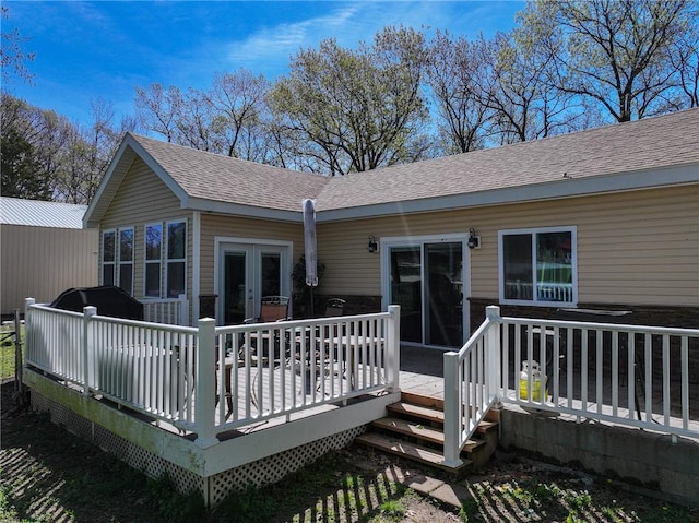 rear view of house featuring a wooden deck, a shingled roof, and french doors