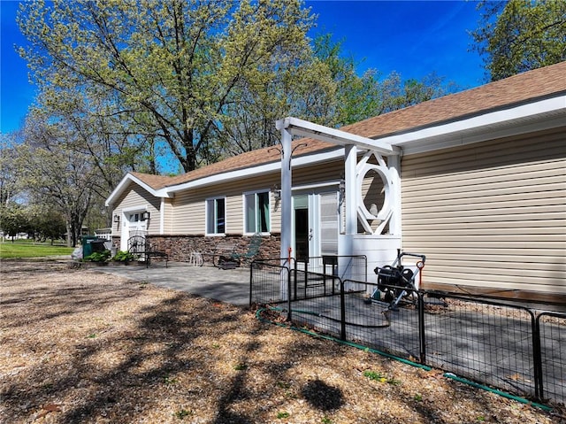 rear view of property featuring fence, roof with shingles, and a patio area