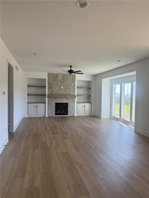 8913 N Colorado Ave, Kansas City, MO 64156 - unfurnished living room featuring built in shelves, a ceiling fan, wood finished floors, and a tiled fireplace