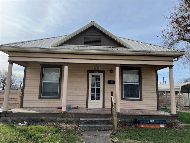 206 W 4th St, Norborne, MO 64668 - shotgun-style home featuring a porch, metal roof, and fence