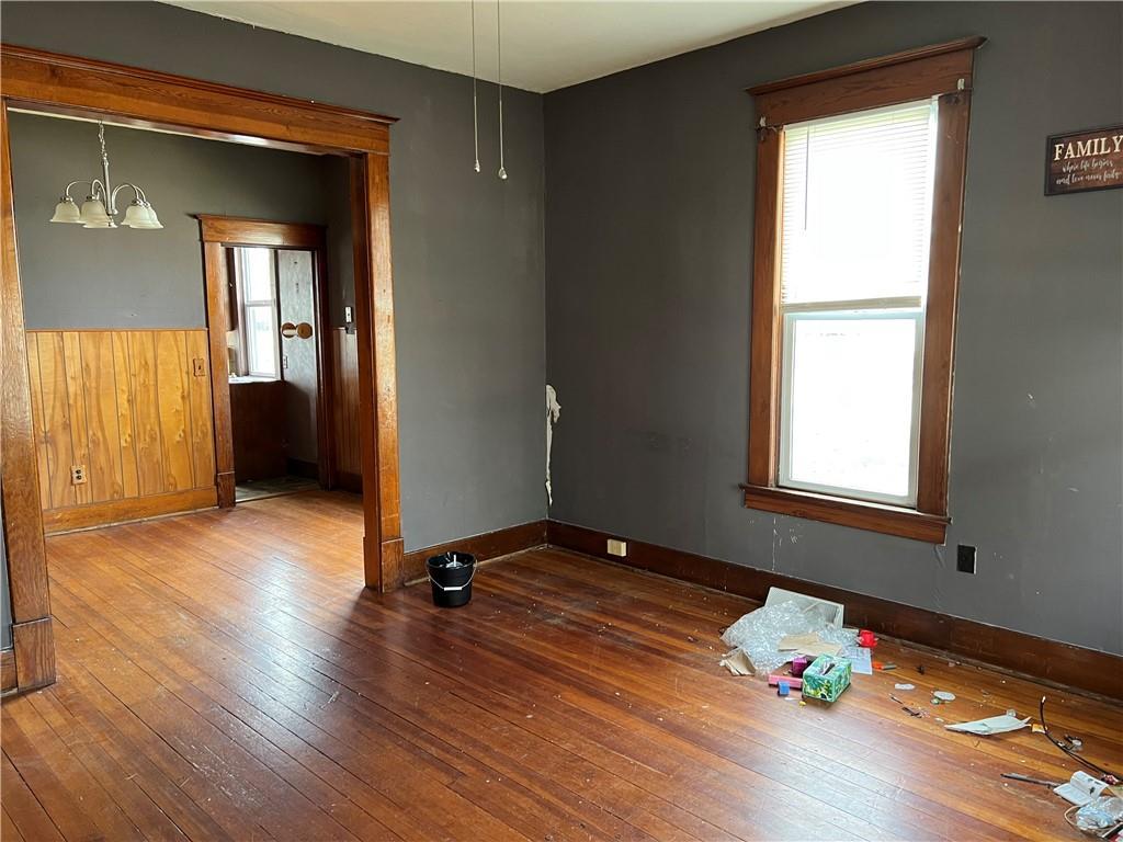 206 W 4th St, Norborne, MO 64668 - unfurnished room with plenty of natural light, a chandelier, hardwood / wood-style flooring, and baseboards