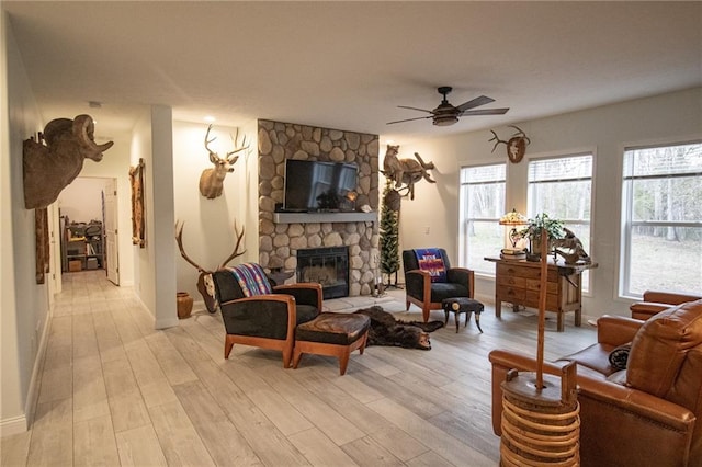 10200 SE 1075th Rd, Collins, MO 64738 - living room with ceiling fan, light wood finished floors, a stone fireplace, and baseboards