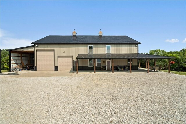back of property featuring driveway, a chimney, metal roof, and a garage
