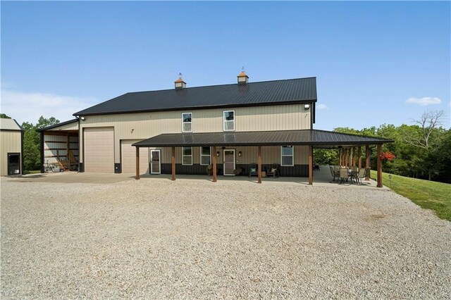 rear view of house featuring metal roof, a chimney, and driveway
