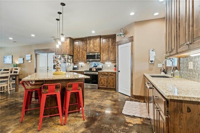 kitchen with appliances with stainless steel finishes, a sink, concrete floors, tasteful backsplash, and light stone countertops