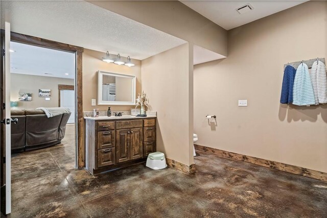 bathroom featuring toilet, baseboards, vanity, and concrete flooring