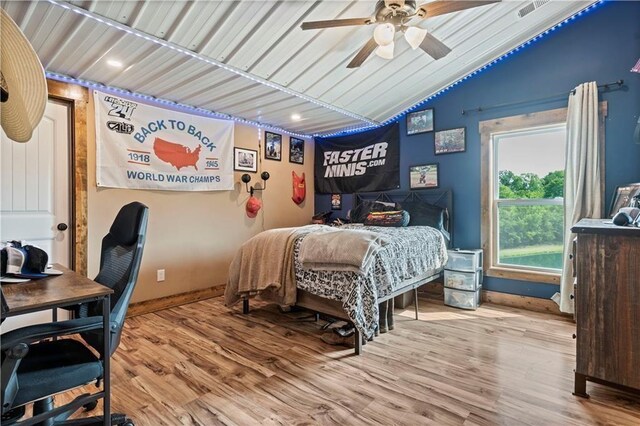 bedroom with lofted ceiling, wood finished floors, an office area, and ceiling fan