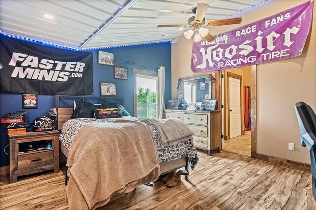bedroom featuring lofted ceiling, light wood finished floors, a ceiling fan, and baseboards