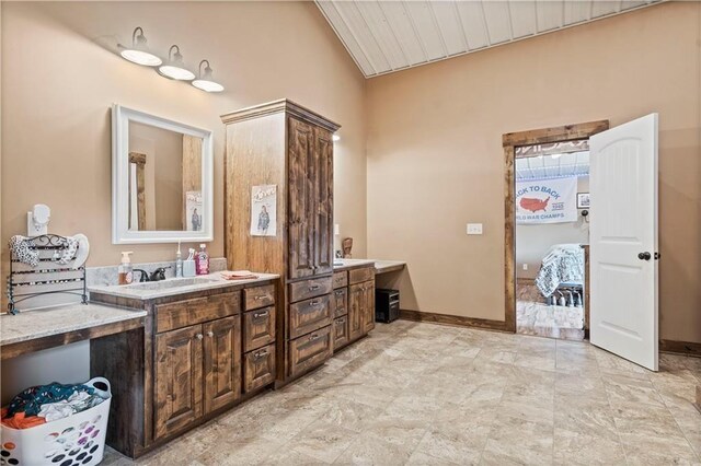bathroom featuring lofted ceiling, vanity, and baseboards