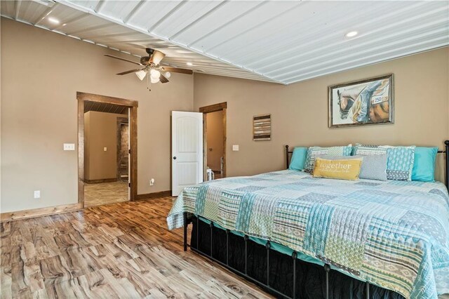 bedroom with wood finished floors, vaulted ceiling, and baseboards