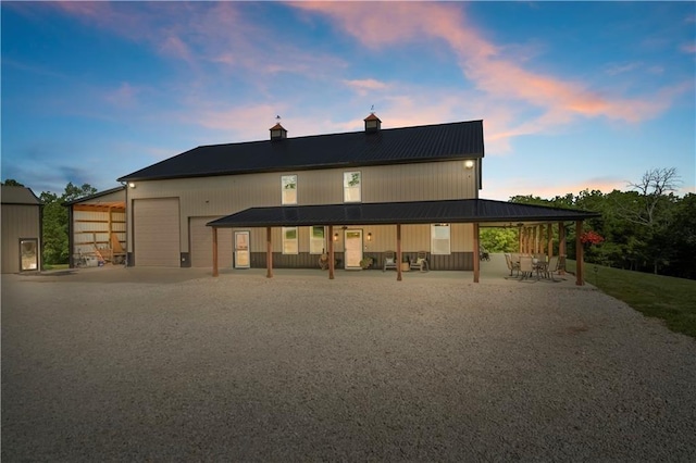 back of property at dusk with a chimney, metal roof, and a garage