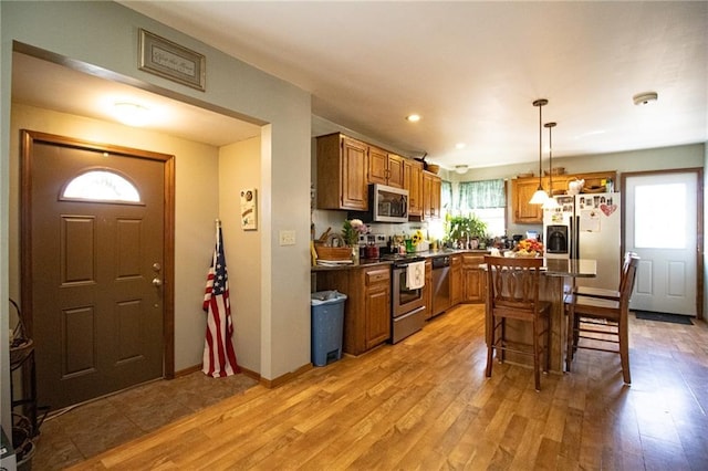 10875 SE 54th Hwy, Collins, MO 64738 - kitchen with stainless steel appliances, light wood-style flooring, a kitchen breakfast bar, brown cabinetry, and dark countertops