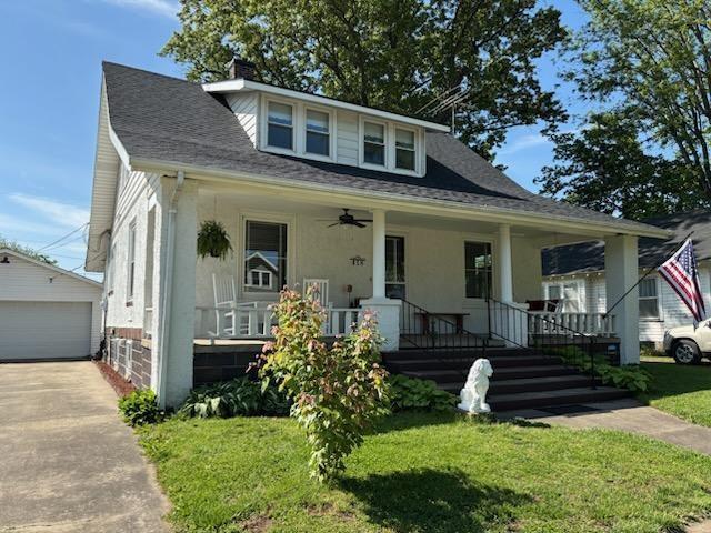 bungalow-style house featuring covered porch, an outdoor structure, a front yard, and ceiling fan