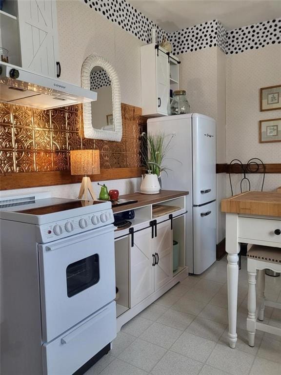 kitchen featuring white appliances, range hood, white cabinets, backsplash, and open shelves