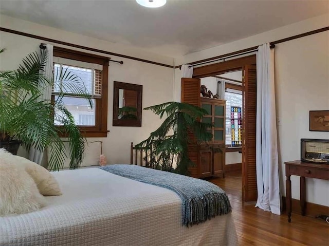 bedroom featuring wood finished floors and multiple windows