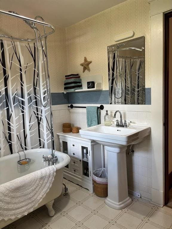bathroom with tile walls, a freestanding tub, tile patterned floors, curtained shower, and wainscoting