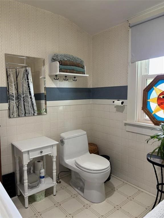 bathroom with toilet, tile patterned floors, tile walls, a wainscoted wall, and a shower with shower curtain