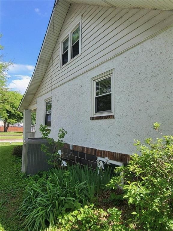 view of side of property featuring stucco siding and central air condition unit