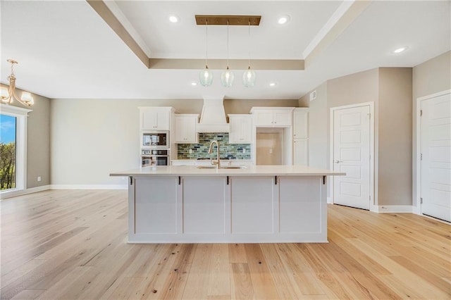 10201 N Winchester Ave, Kansas City, MO 64156 - kitchen with a tray ceiling, built in microwave, light countertops, white cabinetry, and a large island with sink