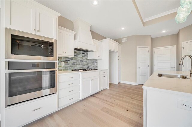 10201 N Winchester Ave, Kansas City, MO 64156 - kitchen featuring stainless steel appliances, a sink, light wood finished floors, decorative backsplash, and white cabinets