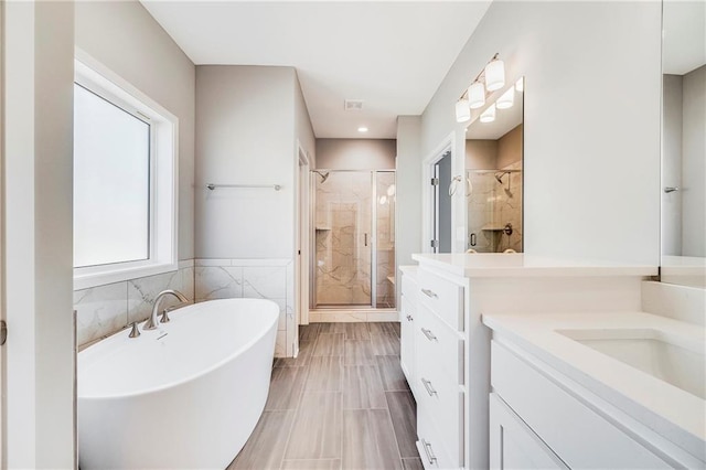 10201 N Winchester Ave, Kansas City, MO 64156 - full bathroom featuring a shower stall, vanity, a freestanding tub, tile walls, and wainscoting