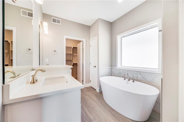 10201 N Winchester Ave, Kansas City, MO 64156 - bathroom featuring a walk in closet, a freestanding tub, tile walls, and vanity