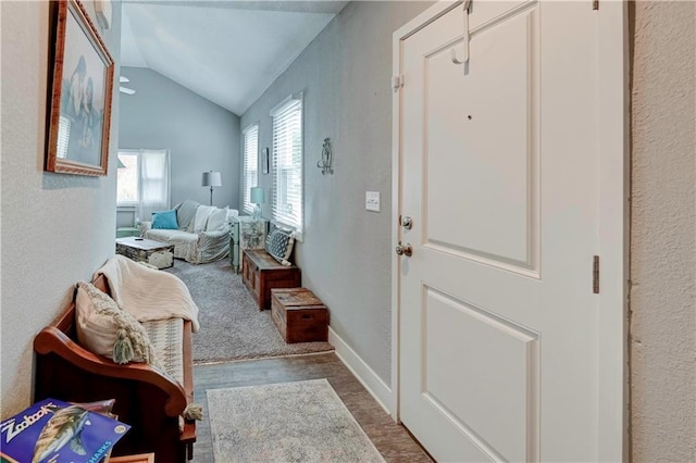 entrance foyer with vaulted ceiling, wood finished floors, a textured wall, and baseboards