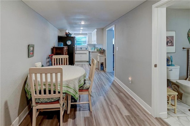 dining space with baseboards and light wood-style floors