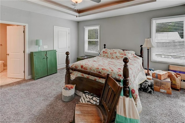 bedroom with carpet floors, a raised ceiling, and a ceiling fan