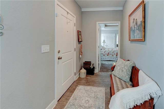 corridor featuring wood finished floors, baseboards, and ornamental molding