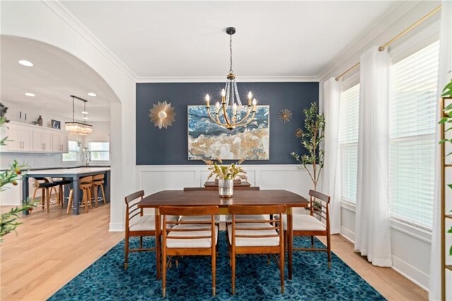 18873 W 168th Ter, Olathe, KS 66062 - dining area with a chandelier, light wood finished floors, a wainscoted wall, ornamental molding, and arched walkways