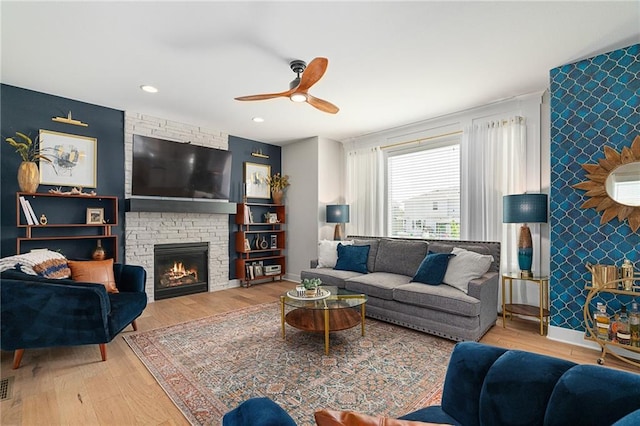 18873 W 168th Ter, Olathe, KS 66062 - living area with an accent wall, wood finished floors, a ceiling fan, a large fireplace, and baseboards