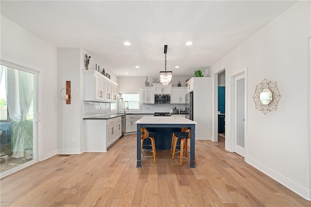 18873 W 168th Ter, Olathe, KS 66062 - kitchen with stainless steel appliances, a sink, a breakfast bar area, backsplash, and light wood-type flooring