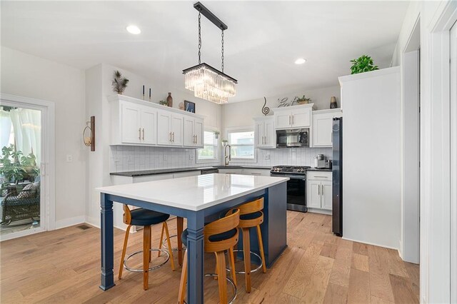 18873 W 168th Ter, Olathe, KS 66062 - kitchen featuring stainless steel appliances, tasteful backsplash, a kitchen bar, a kitchen island, and light wood-style floors