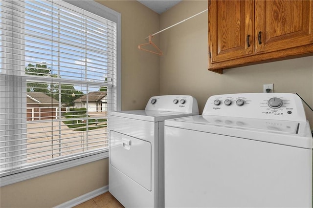 laundry area with cabinet space, washing machine and clothes dryer, light tile patterned floors, and baseboards
