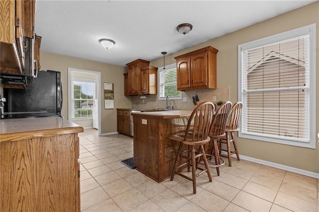 kitchen with baseboards, a peninsula, freestanding refrigerator, and a kitchen bar