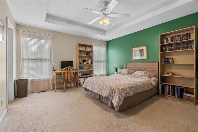bedroom featuring carpet, a tray ceiling, a ceiling fan, and a textured ceiling