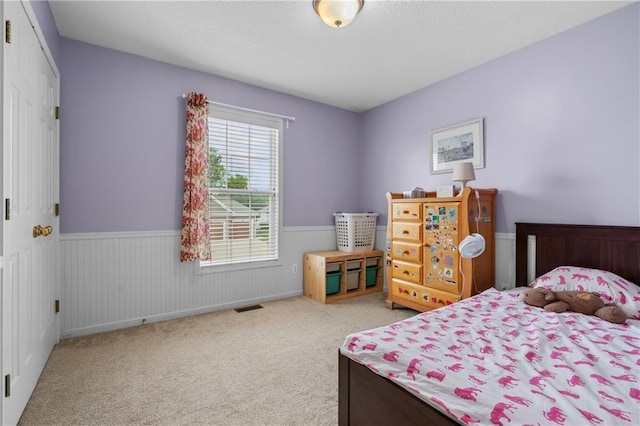 carpeted bedroom featuring a wainscoted wall
