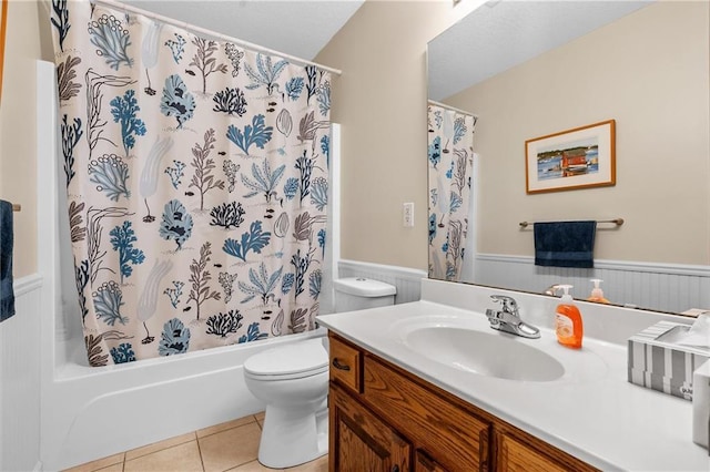 full bathroom with wainscoting, tile patterned floors, toilet, vanity, and shower / bath combo
